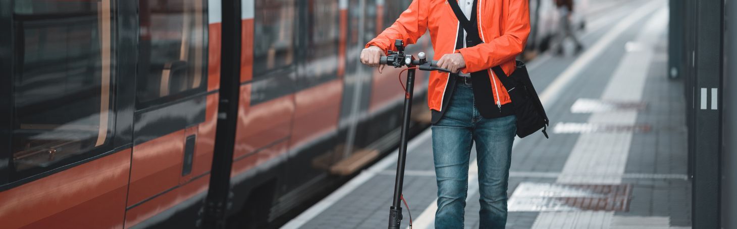 Mężczyzna z hulajnogą elektryczną przy pociągu