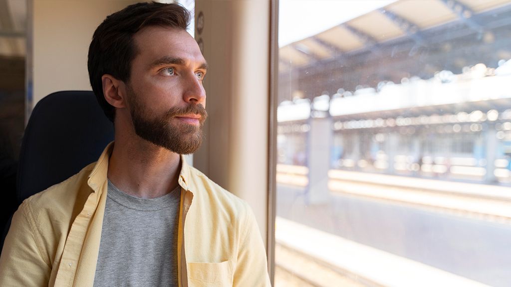 Młody człowiek wyglądający za okno w pociągu