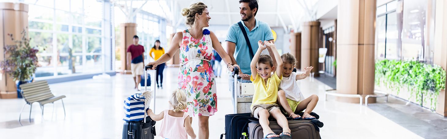 Rodzice z dwójką dzieci i walizkami na dworcu