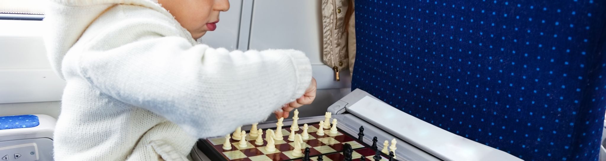 dziecko grające w szachy w pociągu - pomysły na wesołe podróże z dziećmi