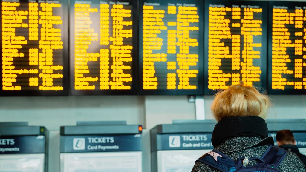 Kobiet patrząca na tablicę odjazdów i przyjazdów